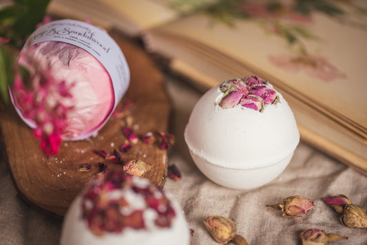 All-natural, Secret Bath Bombs decorated with dried rose buds, wrapped in pink tissue paper. Handmade by The Eden Collections.