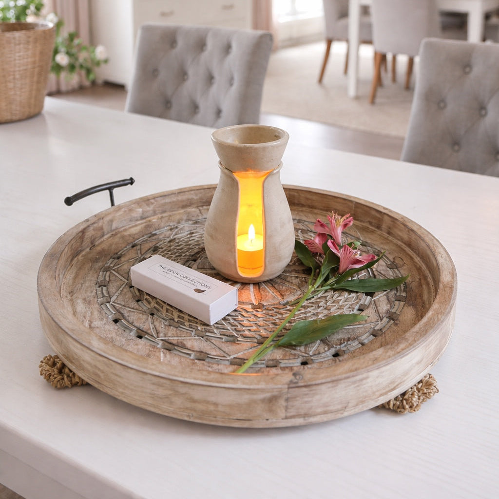 Decorative tray with a lit candle and flowers on a table in a home setting.