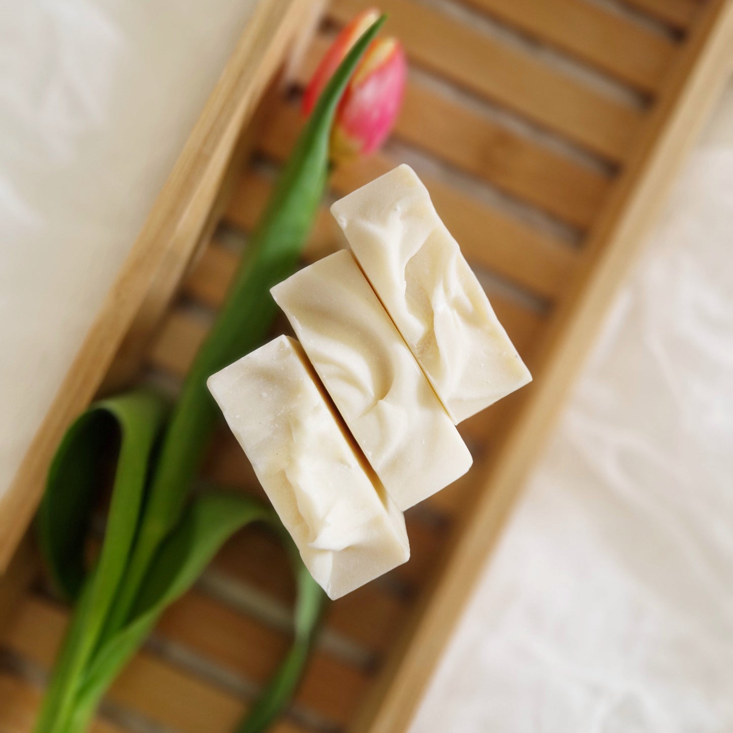 Cloud all natural soap with coconut milk, lavender, and bergamot essential oils. Handmade by The Eden Collections. 3 cloud soaps on a wooden bath tray with a tulip.