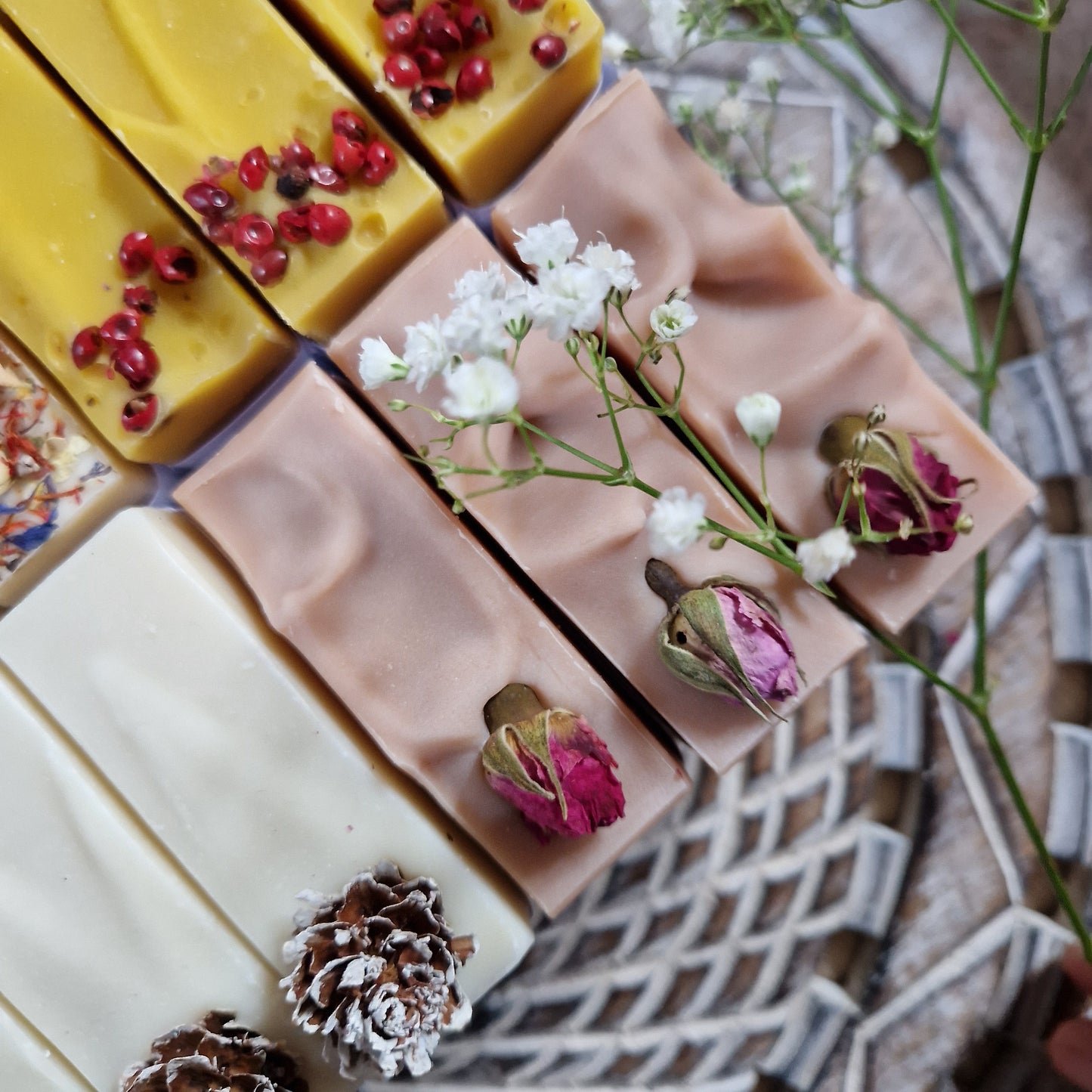 Elegant handmade soap bars from The Eden Collections, decorated with botanicals on the top. They are photographed from the top and placed on a wooden tray.