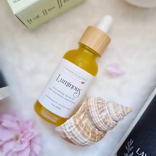 All natural, Luminous facial oil, enriched with watermelon seed oil and other natural oils and essential oils. It is displayed in olden colour with a shell and flowers. Handmade by The Eden Collections.