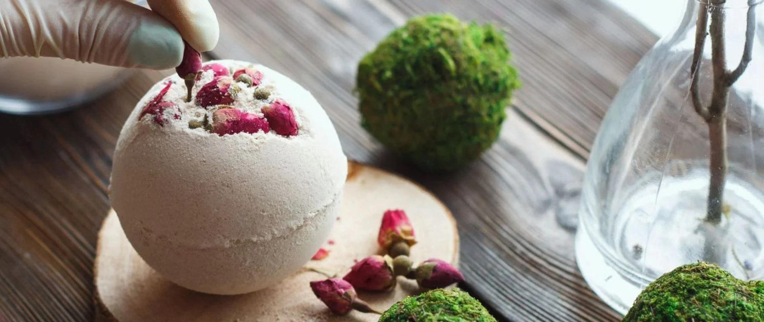 A close up image of The Eden Collections Secret Bath Bombs being made, displayed alongside ingredients laid out on a wooden worktop.