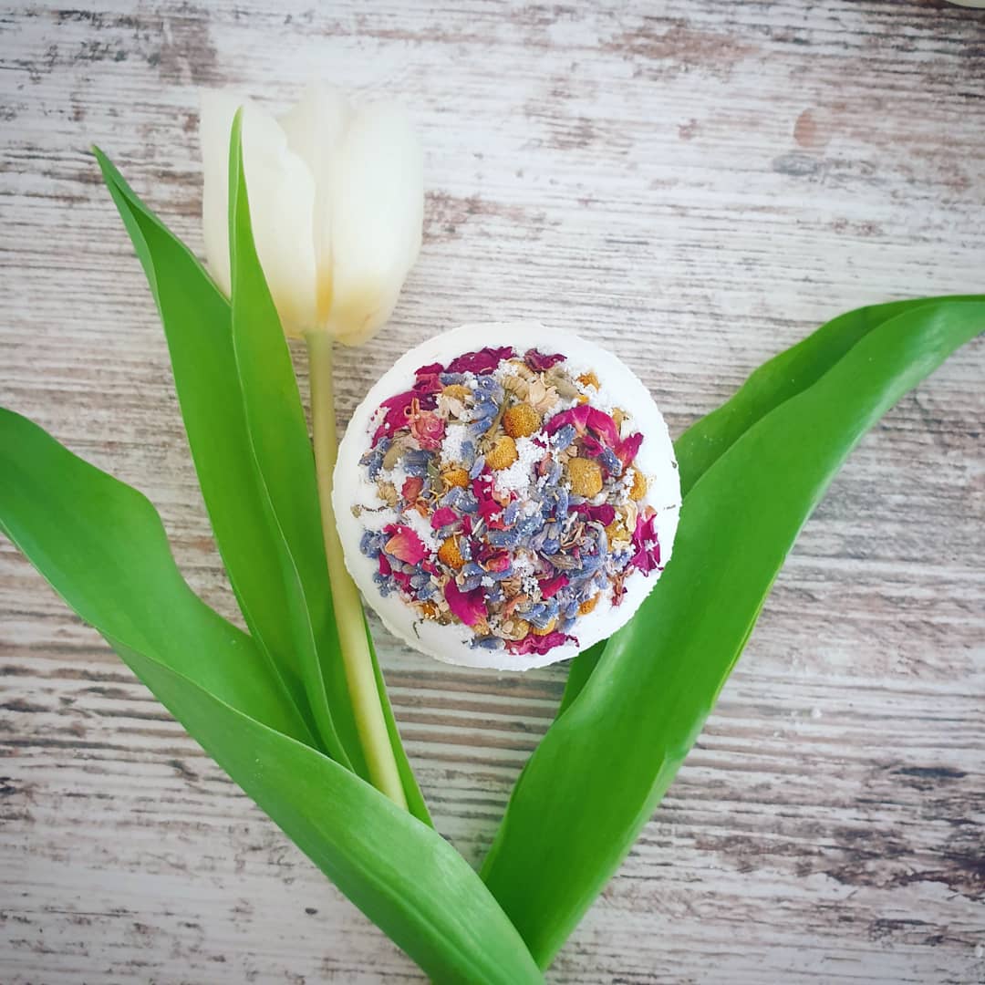 Sweet Dream Secret Bath Bomb, showcased alongside a beautiful flower to represent the essence of this moisturising bath bomb.