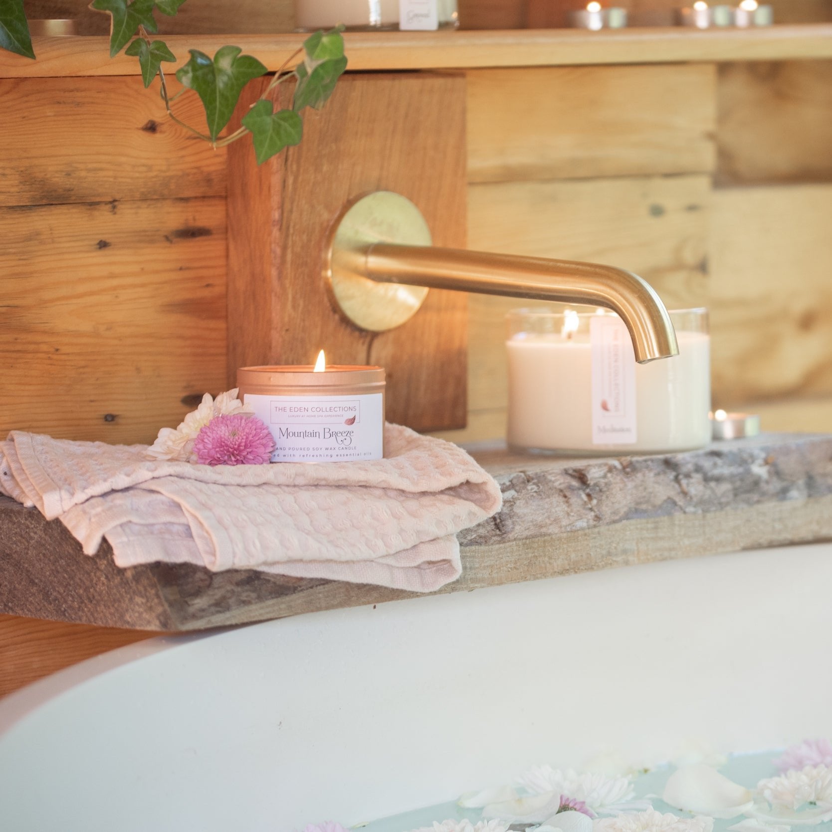 Scented soy wax candle in rose gold tin. The candle is placed on a wood by a bathtub, creating a cosy, luxury atmosphere. Hand poured by The Eden Collections.