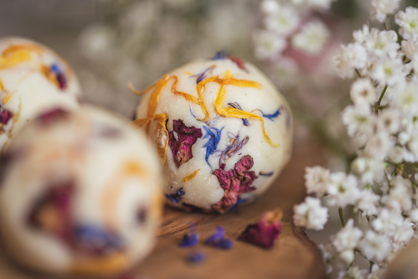 Close up photograph of a handmade bath creamer. It shows the pretty dried botanicals it is decorated with. Handcrafted by The Eden Collections.